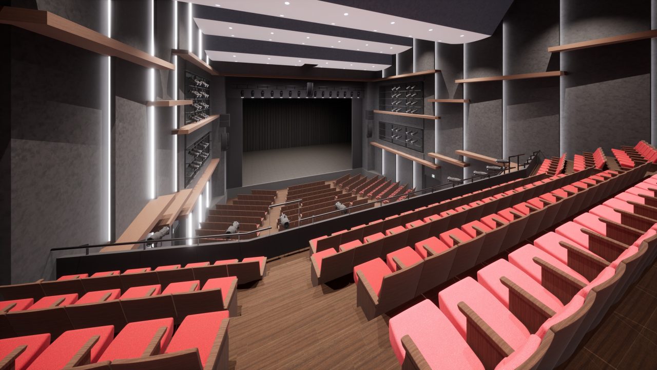 演劇公演利用時のシアター内の画像です。
前方に舞台があり、客席には赤い座席が階段状に並んでいます。劇場内部の壁はグレーで、ライン状の照明と木の板でできた装飾がところどころに施されています。シックな雰囲気の空間です。