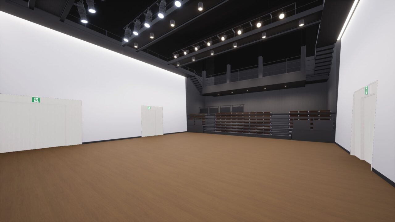 移動観覧席収納時のコモンスペースの画像です。
何も置かれていない茶色の木目の床が広がる空間で、左右の壁は白です。奥の壁は黒に近いグレーで、折りたたんだ状態の客席が壁にそって収納されています。天井は黒く、天井全体に吊り下げ式のスポット照明が均等に取り付けられています。シックな雰囲気の落ち着いた空間です。